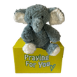 Ari the gray plush comfort elephant gift sitting on a yellow box with 'Praying For You' text