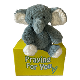 Ari the gray plush comfort elephant gift sitting on a yellow box with 'Praying For You' text
