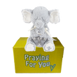 Enzo the gray plush elephant praying toy on a yellow box with 'Praying For You' text.  Christian baby keepsake at sendapraynow.com